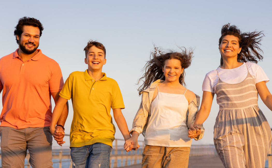 Smiling european millennial parents and teen kids holding hands, enjoy vacation, active lifestyle